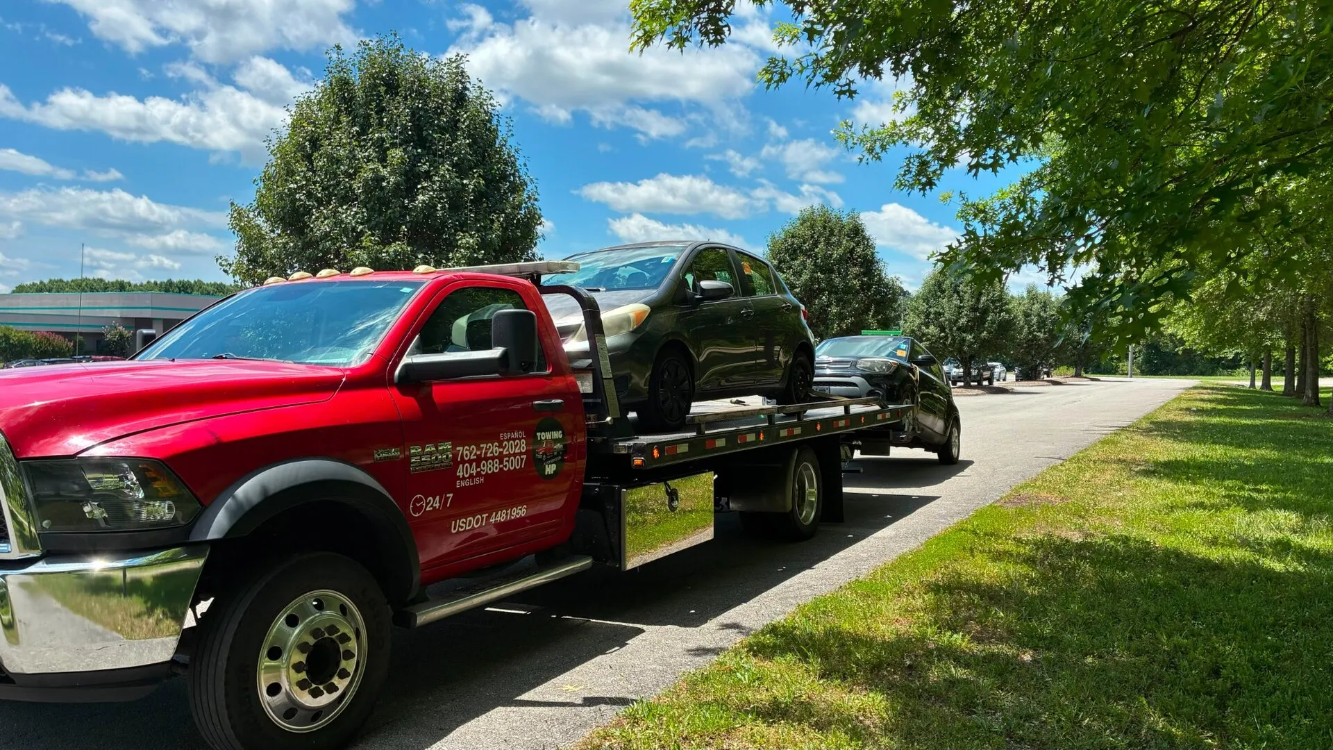Red Ram flatbed tow truck transporting two vehicles in metro Atlanta
